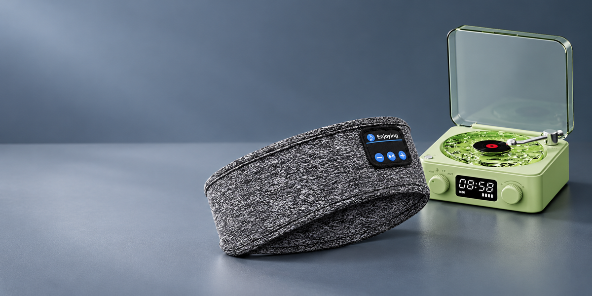 Grey Bluetooth headband and green miniature retro speaker on a blue grey studio background